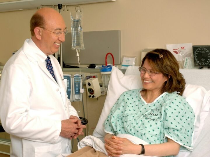 A smiling doctor beside a patient in a hospital bed