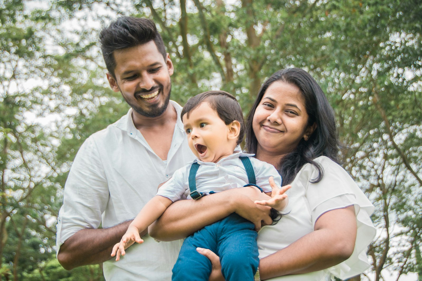 A family of three laughing together outdoors