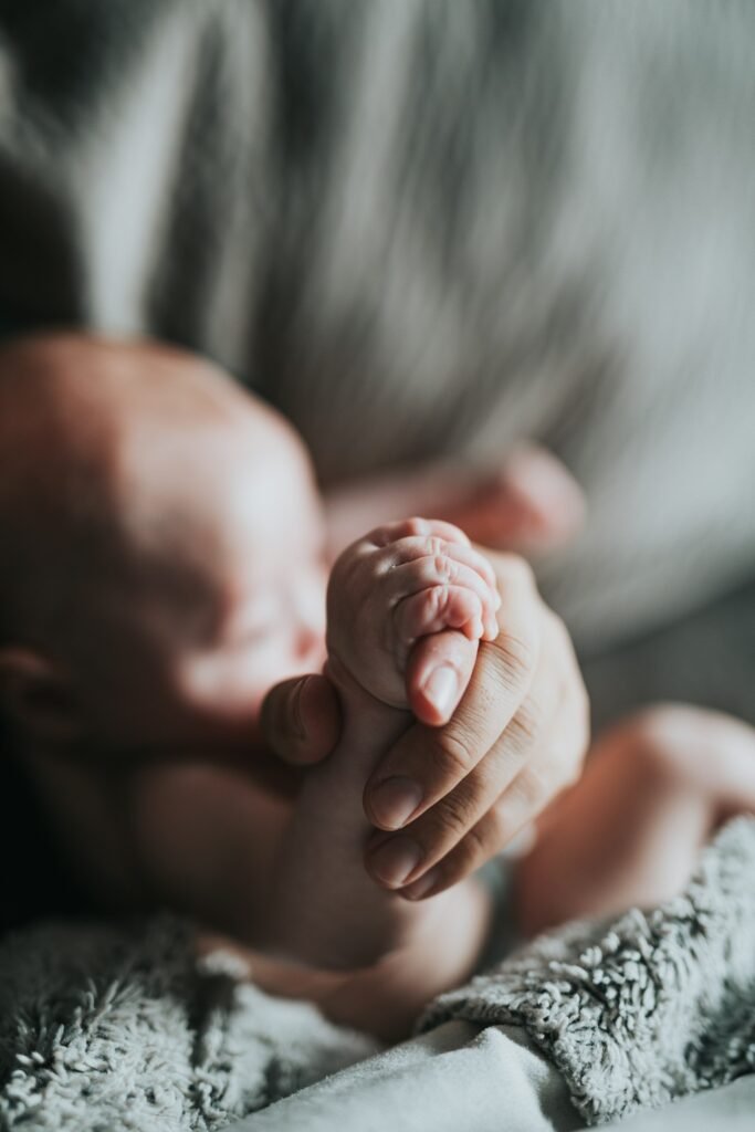A newborn’s hand held by a parent